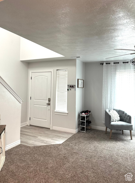 Entryway featuring light colored carpet and a textured ceiling
