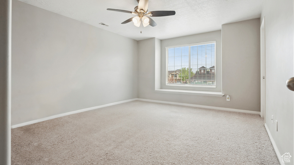 Spare room with light carpet, ceiling fan, and a textured ceiling