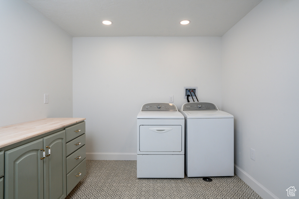 Clothes washing area featuring cabinets, washing machine and dryer, hookup for a washing machine, and light tile floors
