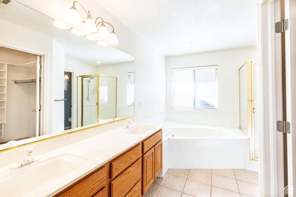 Bathroom with dual sinks, tile flooring, separate shower and tub, and vanity with extensive cabinet space