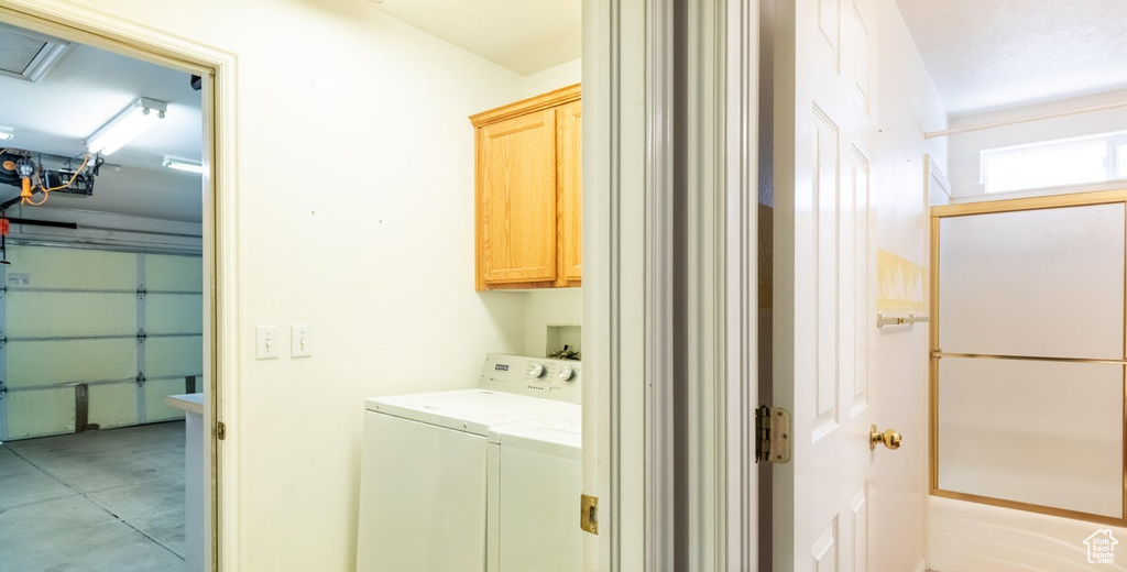 Washroom featuring cabinets, washer hookup, washing machine and dryer, and light tile floors