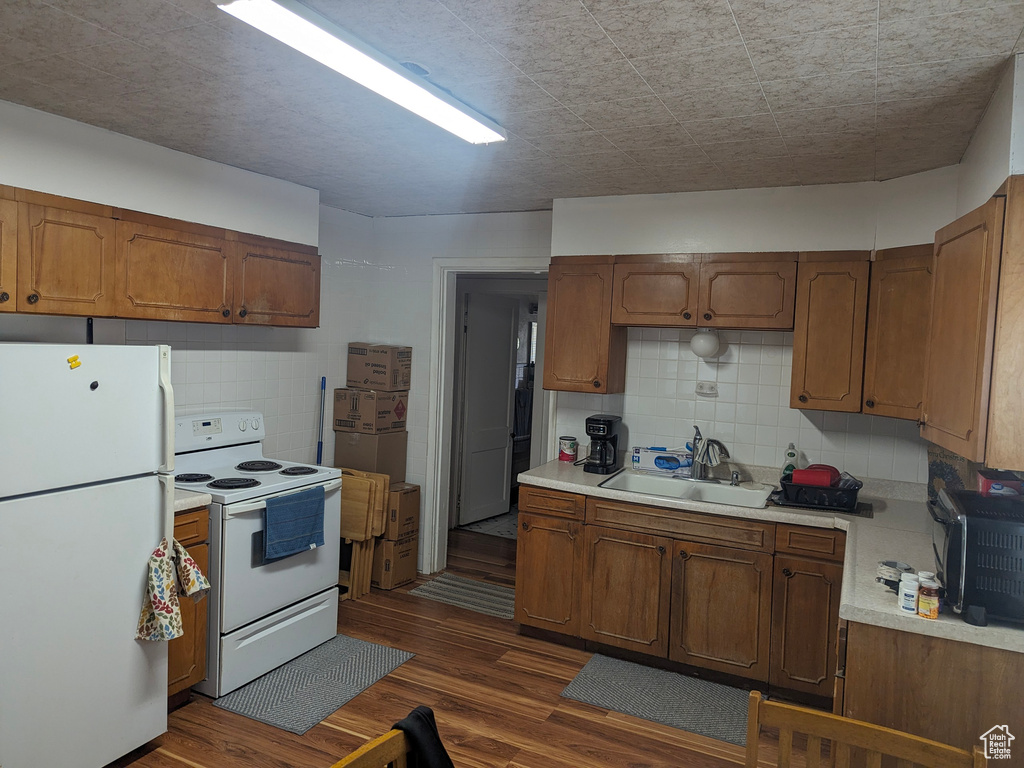 Kitchen featuring backsplash, dark wood-type flooring, white appliances, and sink