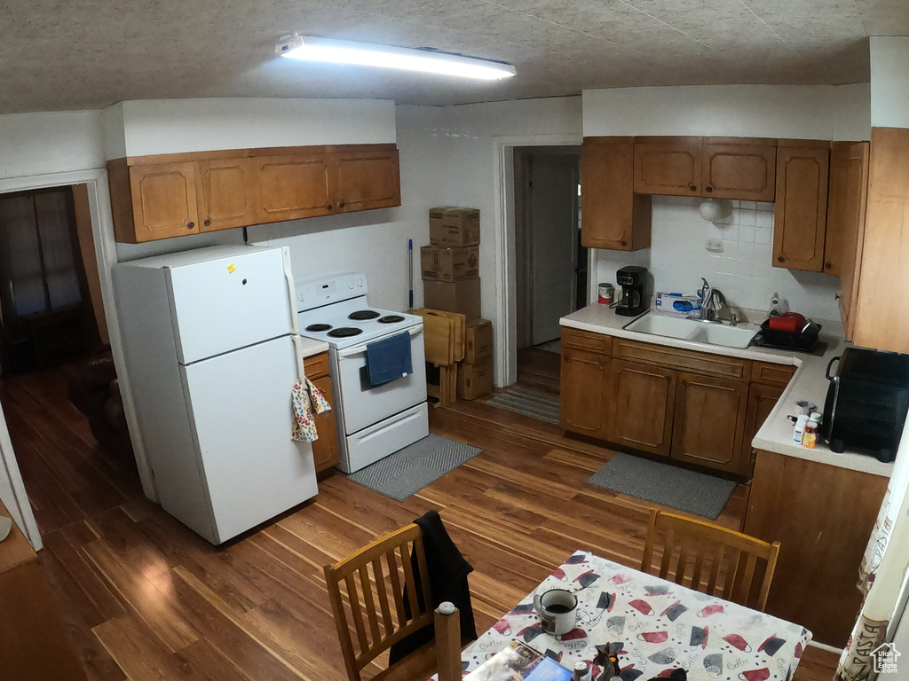 Kitchen featuring sink, white appliances, tasteful backsplash, and dark wood-type flooring