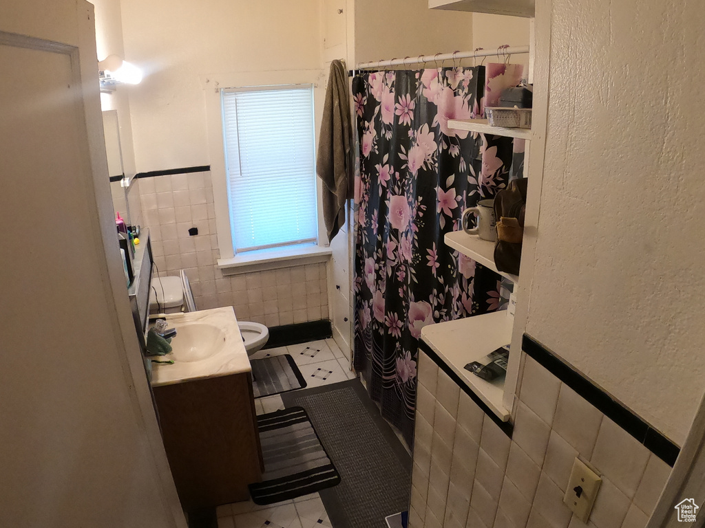 Bathroom featuring tile flooring, tile walls, vanity, and toilet