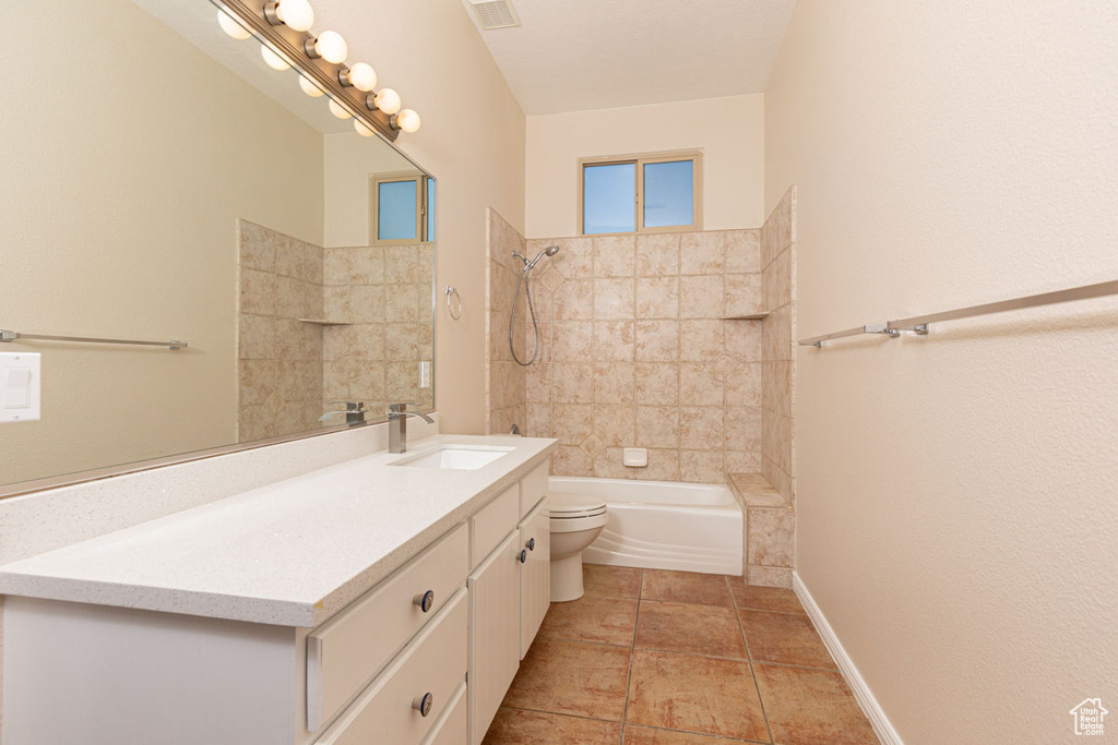 Full bathroom featuring tile flooring, tiled shower / bath, toilet, and large vanity
