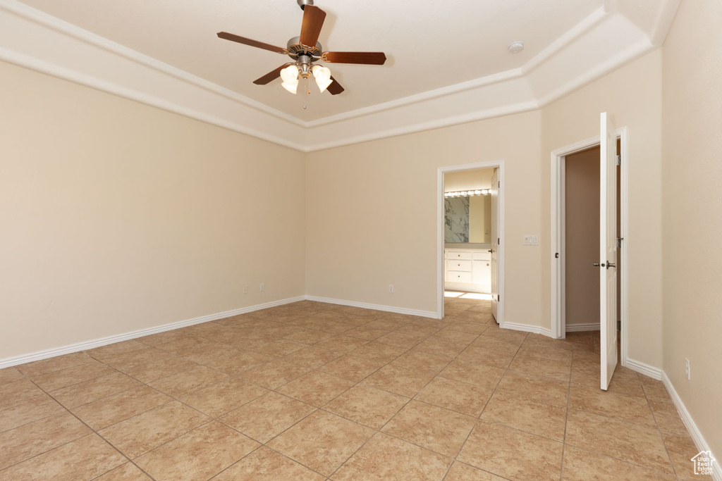 Tiled spare room featuring ceiling fan and a tray ceiling