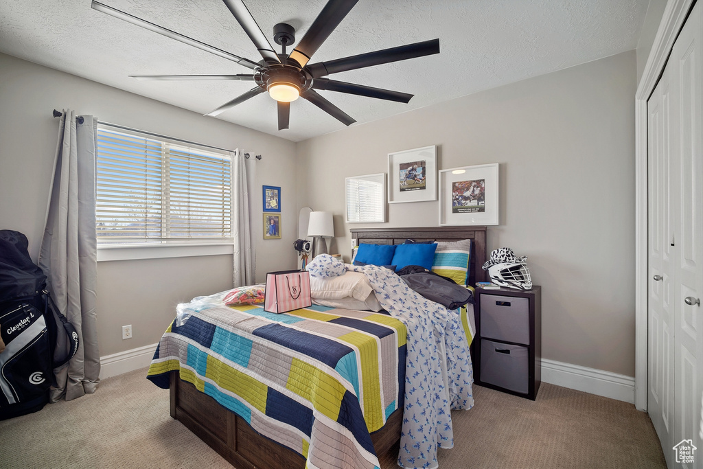 Bedroom with a closet, light carpet, and ceiling fan