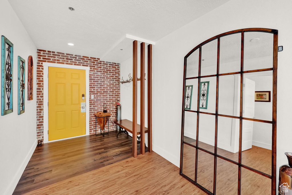 Entryway featuring brick wall, light wood-type flooring, and a textured ceiling