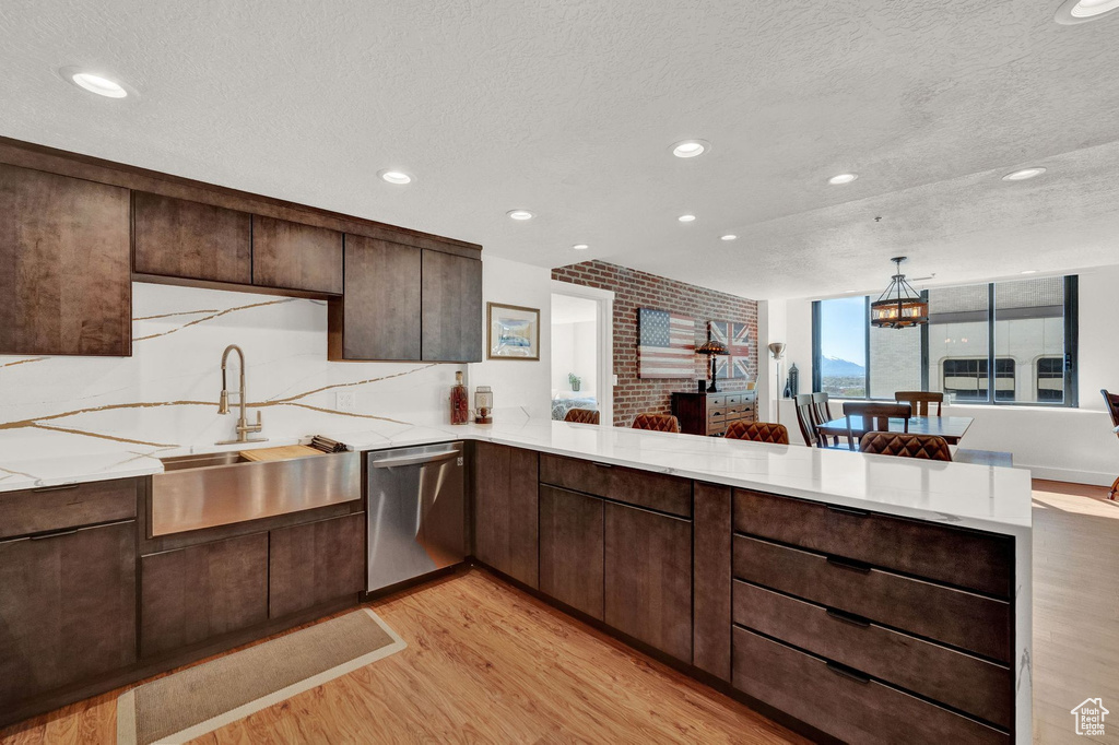 Kitchen with a textured ceiling, light hardwood / wood-style floors, dishwasher, and kitchen peninsula