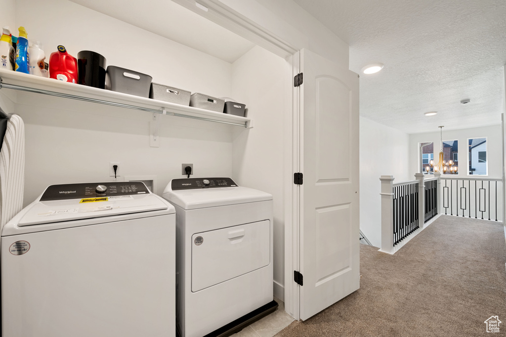 Laundry room featuring a textured ceiling, light carpet, independent washer and dryer, electric dryer hookup, and an inviting chandelier