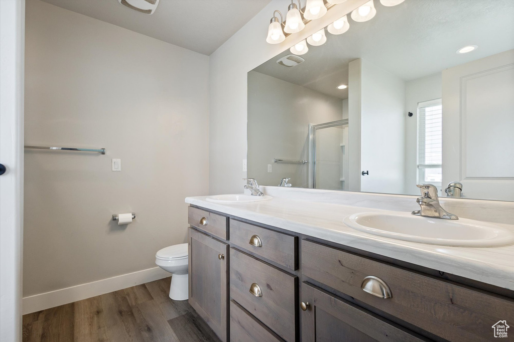 Bathroom featuring hardwood / wood-style flooring, toilet, and dual vanity