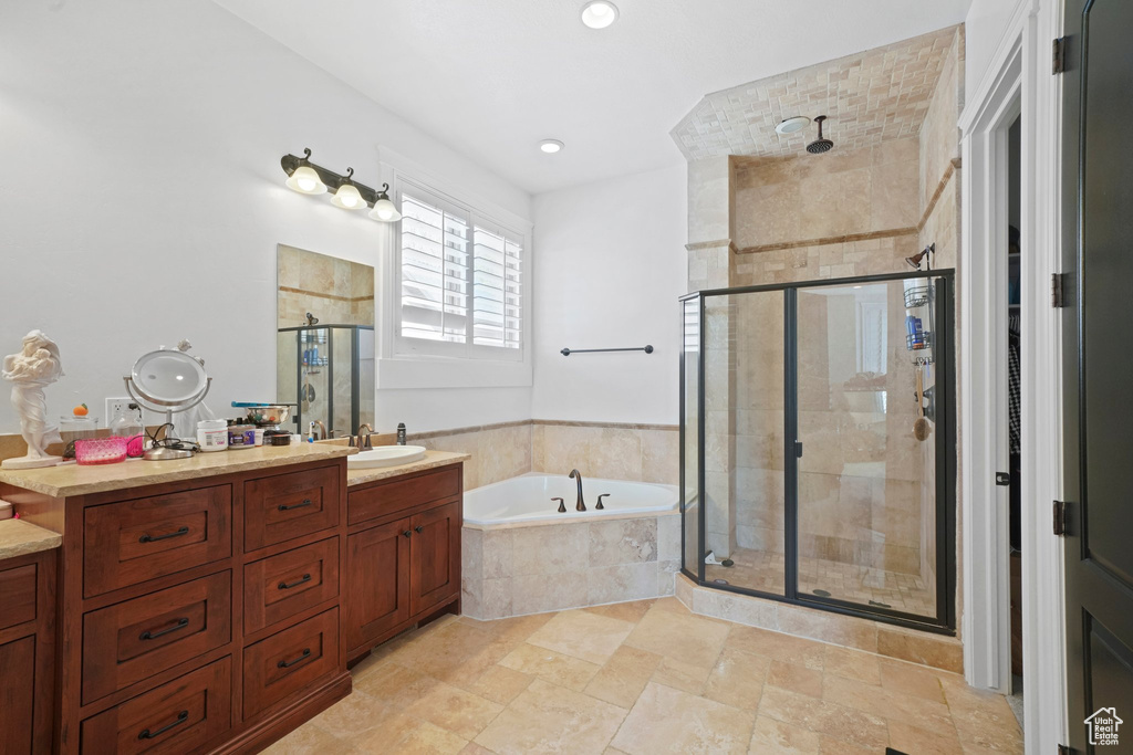 Bathroom featuring dual sinks, oversized vanity, shower with separate bathtub, and tile floors
