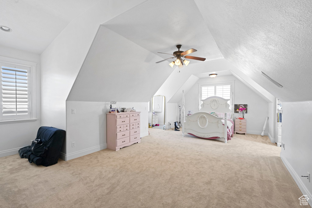 Carpeted bedroom featuring lofted ceiling, ceiling fan, and a textured ceiling