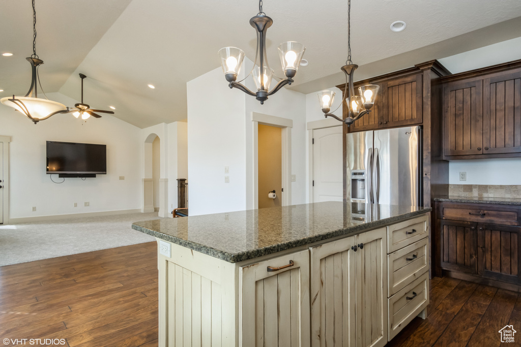 Kitchen featuring dark colored carpet, pendant lighting, a center island, and stainless steel fridge