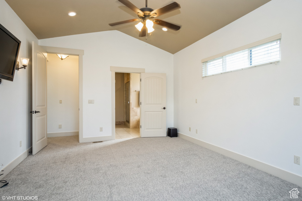 Unfurnished bedroom with light colored carpet, vaulted ceiling, ceiling fan, and ensuite bath