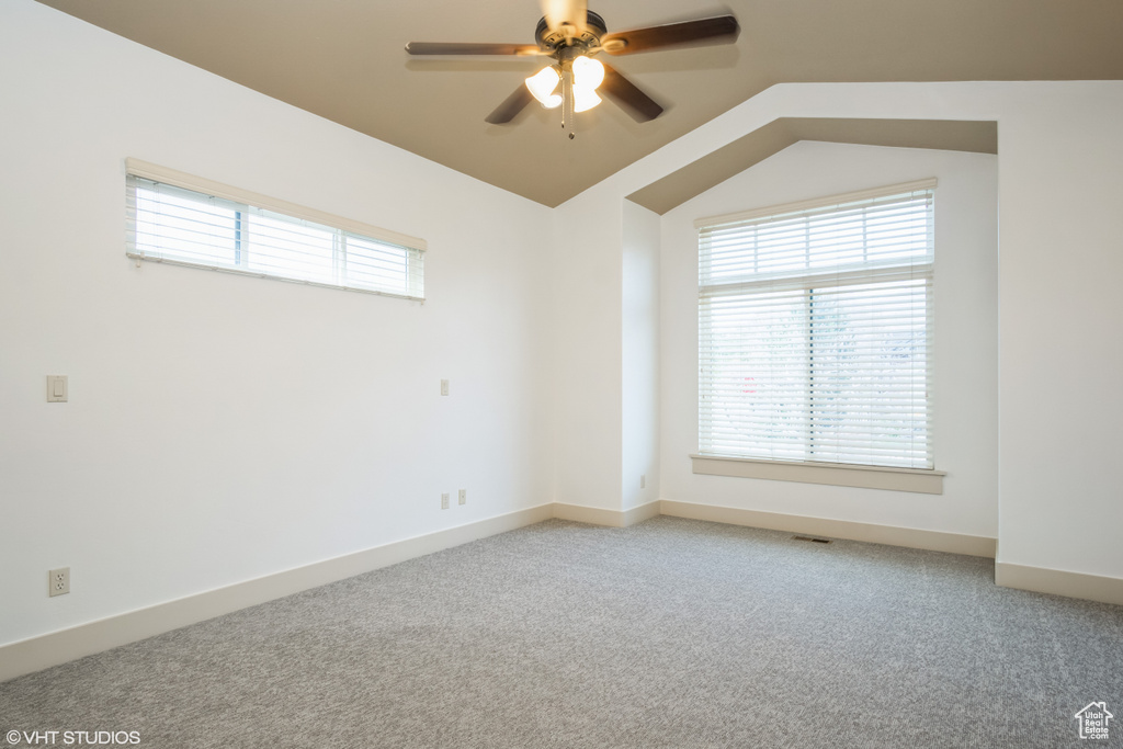 Carpeted spare room with a healthy amount of sunlight, lofted ceiling, and ceiling fan