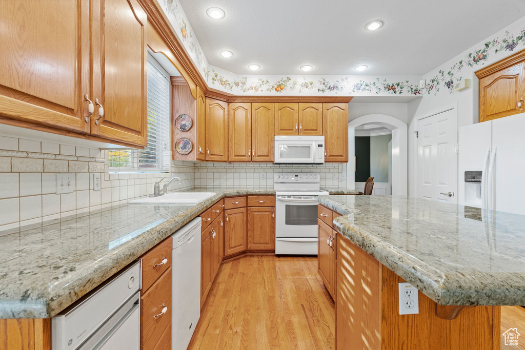 Kitchen featuring a kitchen island, light hardwood / wood-style flooring, white appliances, and sink