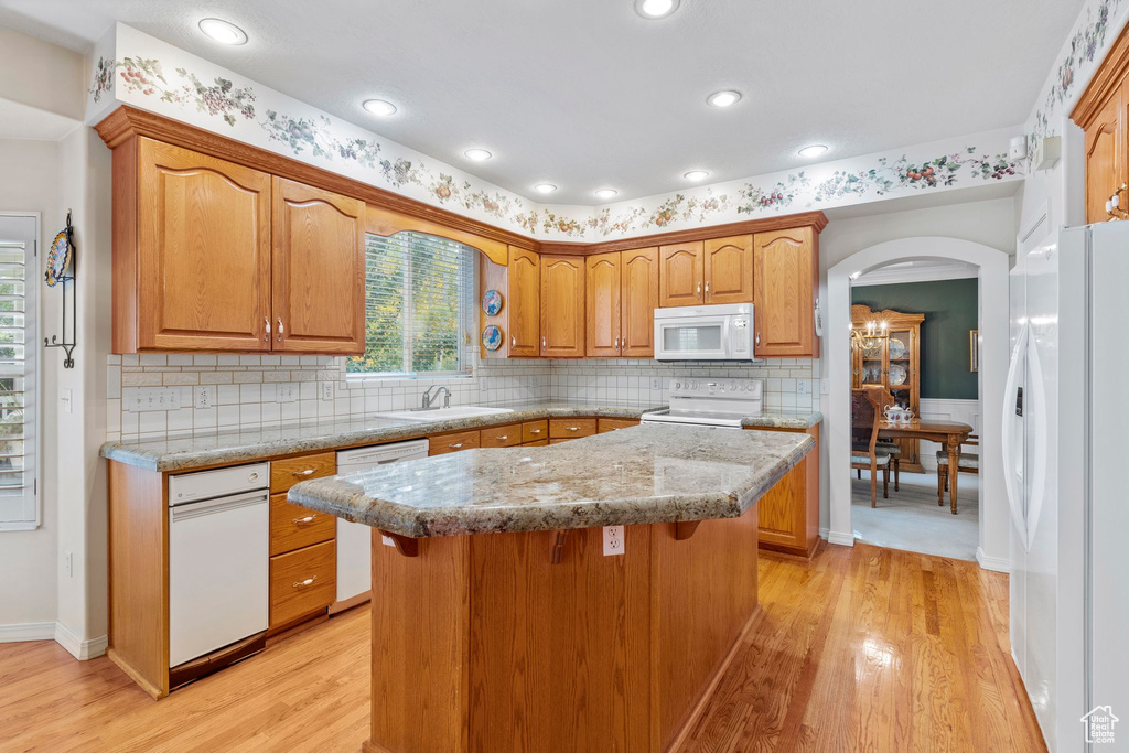 Kitchen featuring a kitchen island, tasteful backsplash, light hardwood / wood-style flooring, and white appliances