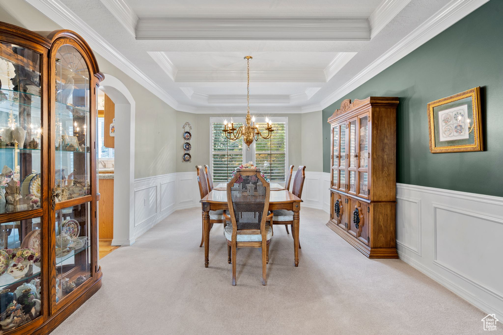 Dining room featuring ornamental molding, an inviting chandelier, light carpet, and a tray ceiling