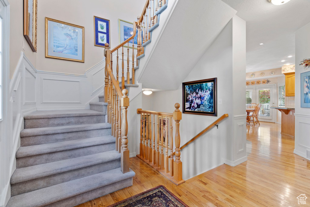 Stairs featuring light hardwood / wood-style floors and a high ceiling