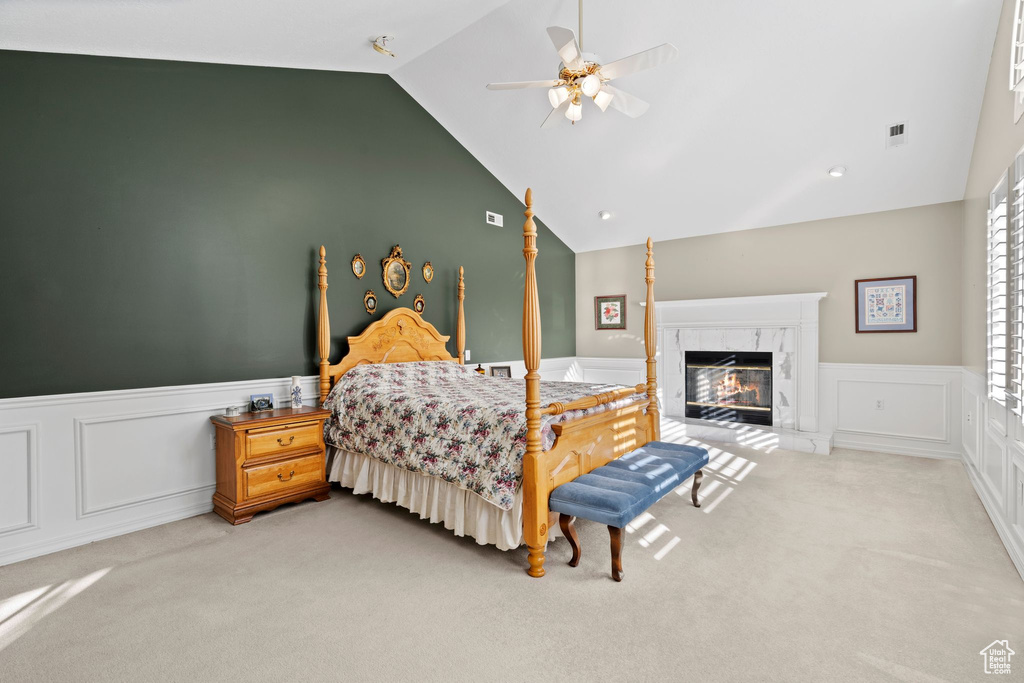 Carpeted bedroom with high vaulted ceiling, ceiling fan, and a fireplace