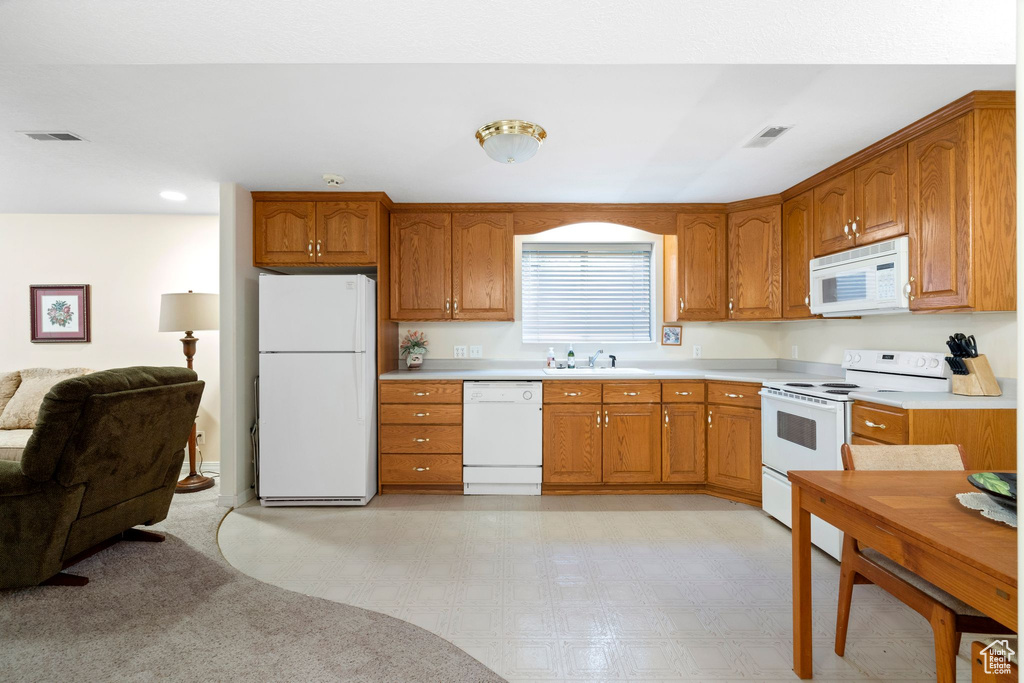 Kitchen featuring light colored carpet, white appliances, and sink