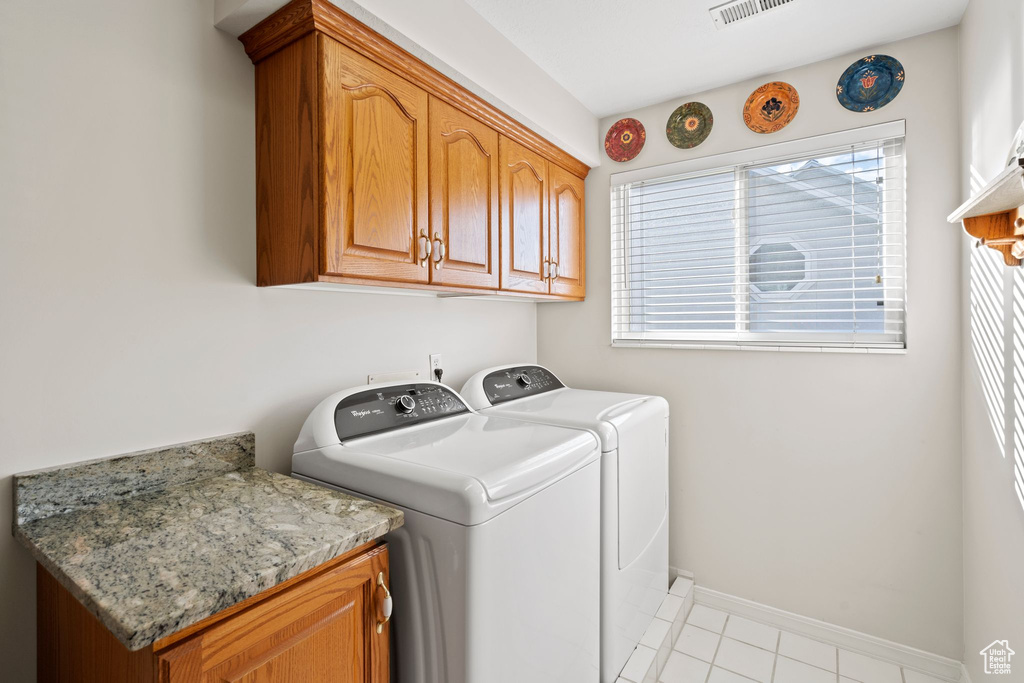 Laundry area with plenty of natural light, washing machine and clothes dryer, cabinets, and light tile floors