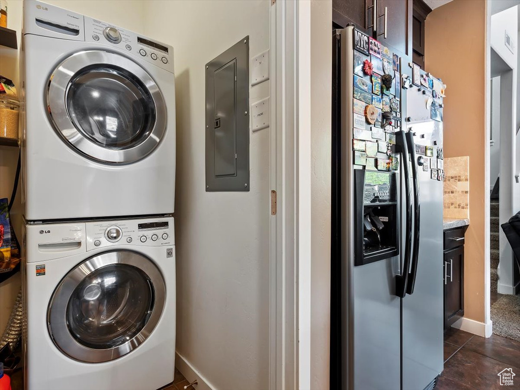 Washroom featuring stacked washer / dryer and dark tile flooring