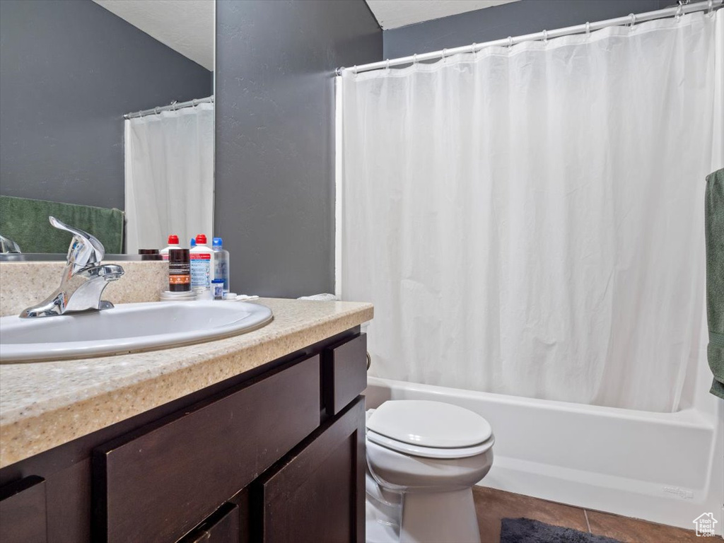 Full bathroom with shower / bath combo, toilet, vanity with extensive cabinet space, and tile flooring