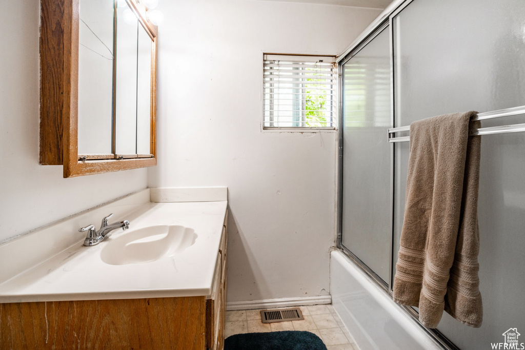Bathroom with vanity, tile floors, and bath / shower combo with glass door