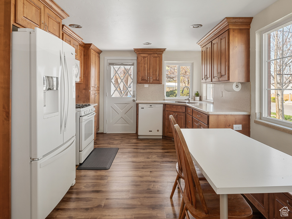 Kitchen with sink, white appliances, and dark wood-type flooring