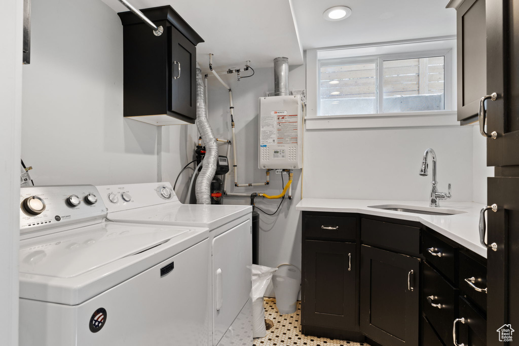 Laundry room with washing machine and dryer, water heater, sink, light tile floors, and cabinets