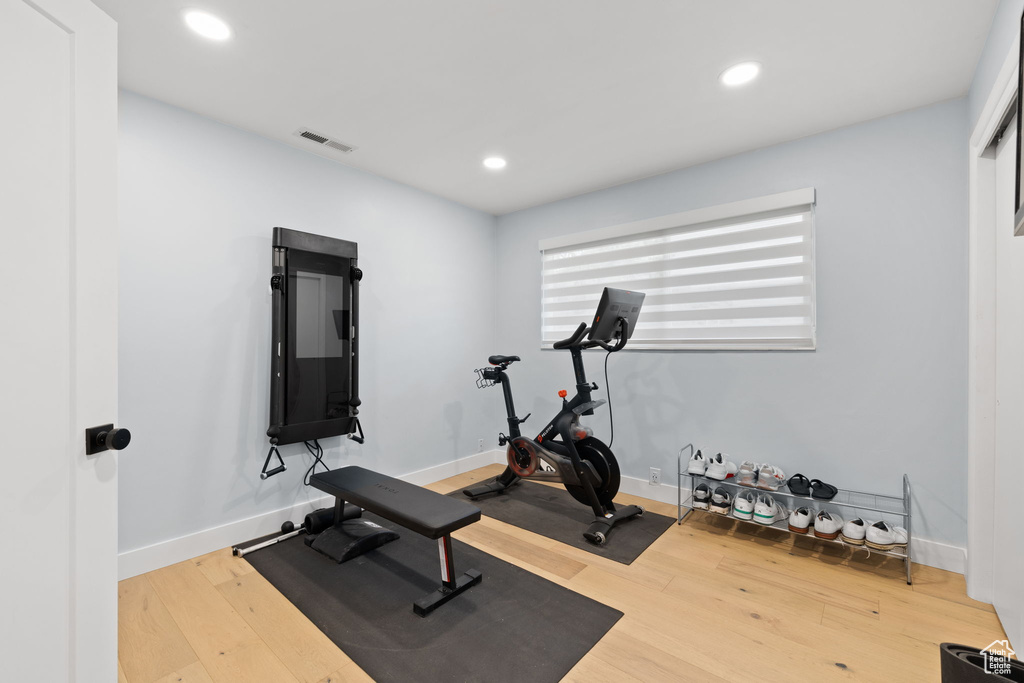 Exercise room with light hardwood / wood-style floors