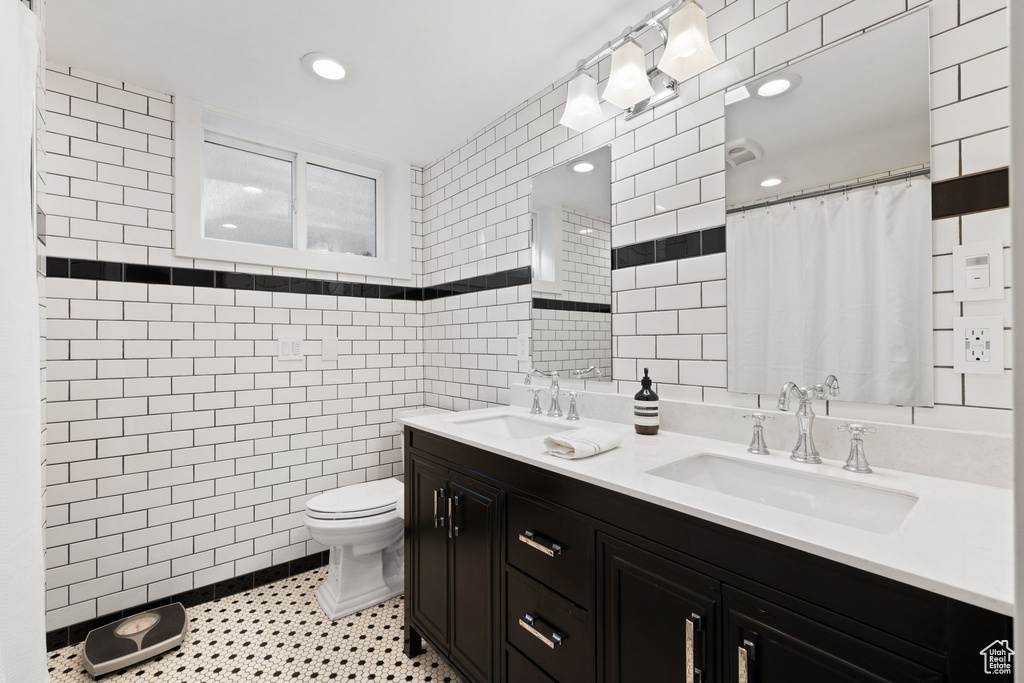 Bathroom with dual sinks, tile walls, tile floors, and large vanity