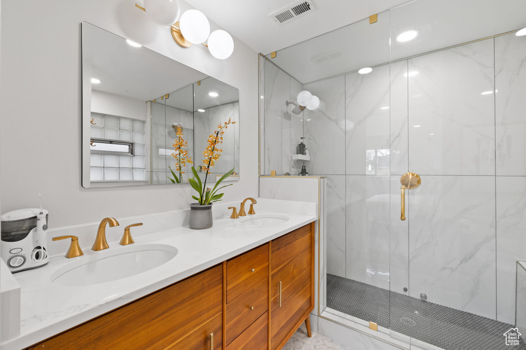 Bathroom with an enclosed shower, vanity with extensive cabinet space, and double sink