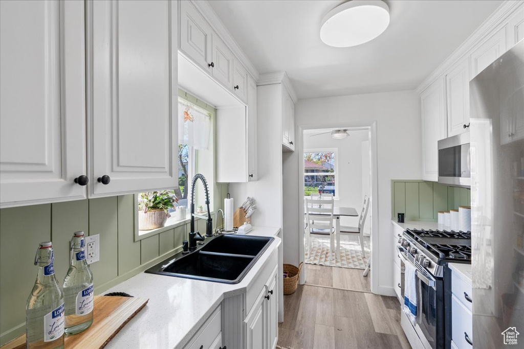 Kitchen featuring sink, plenty of natural light, white cabinetry, and stainless steel appliances