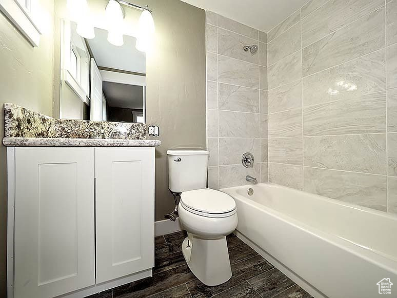 Full bathroom with hardwood / wood-style flooring, vanity, toilet, and tiled shower / bath