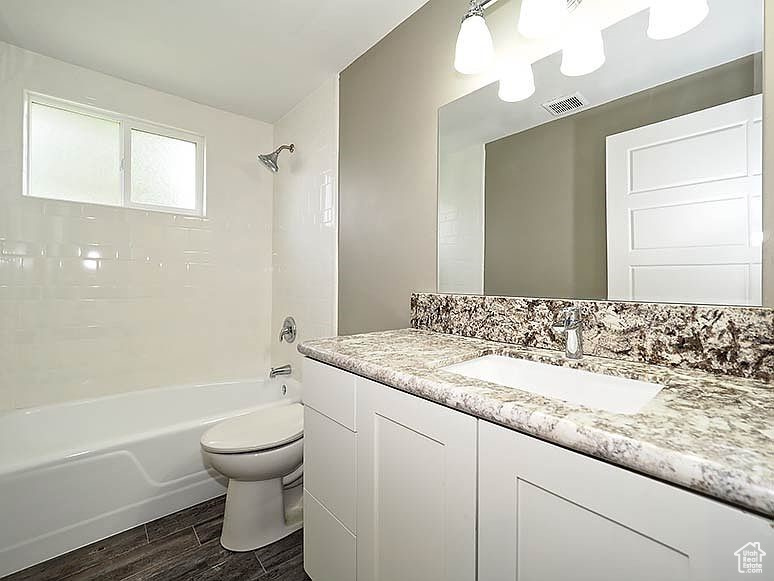 Full bathroom with tiled shower / bath, toilet, and vanity
