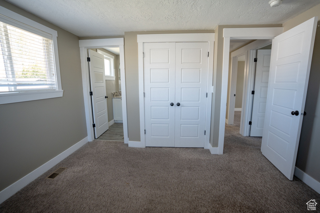 Unfurnished bedroom featuring a closet, dark carpet, and a textured ceiling