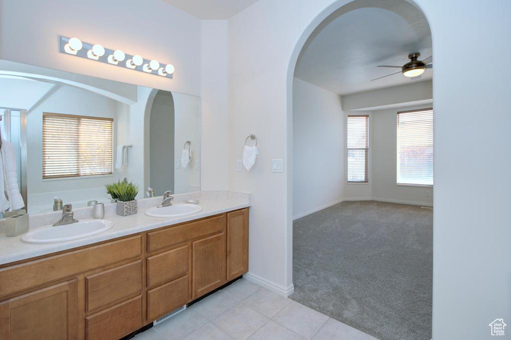 Bathroom with ceiling fan, tile floors, vanity with extensive cabinet space, and dual sinks