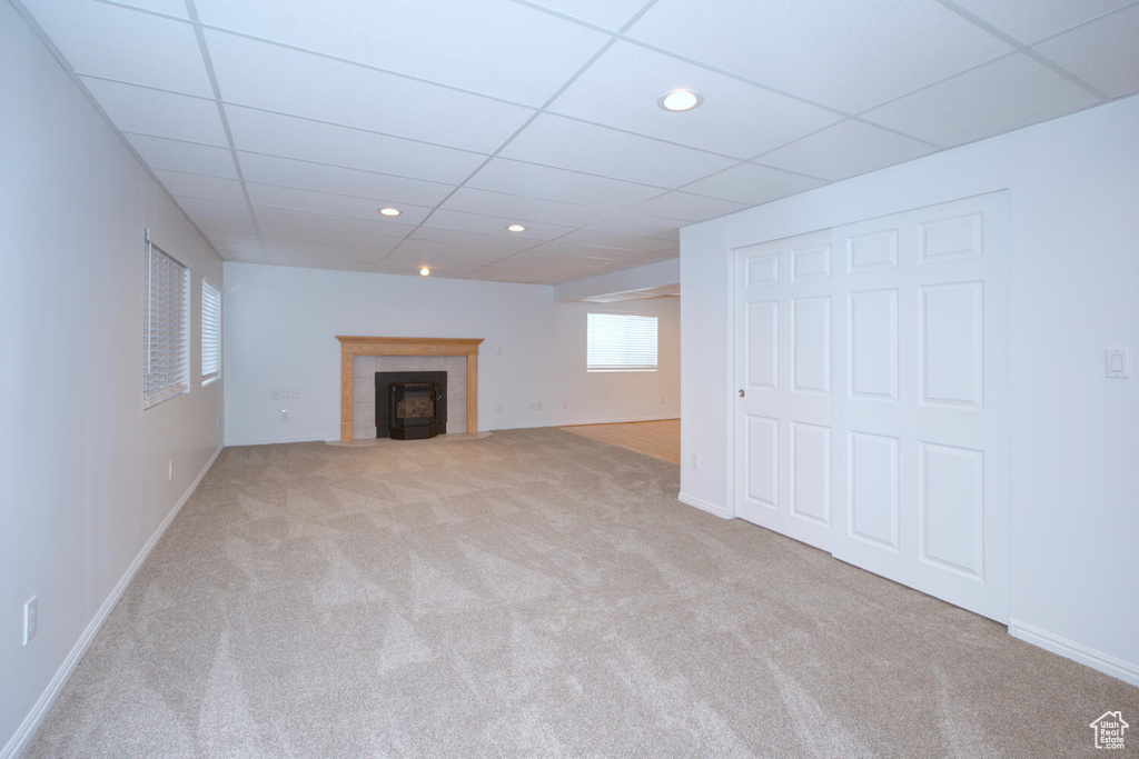 Basement featuring a paneled ceiling, light carpet, and a tiled fireplace