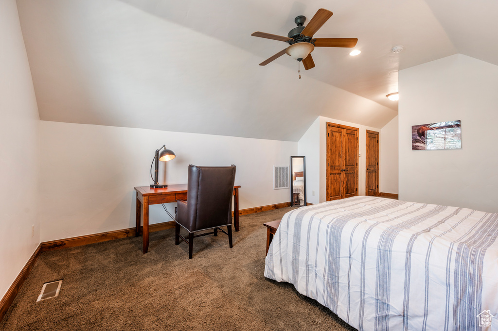 Bedroom with ceiling fan, dark carpet, and lofted ceiling