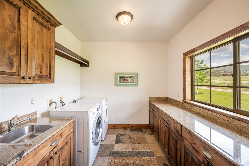 Laundry room with a healthy amount of sunlight, washing machine and dryer, sink, and light tile flooring