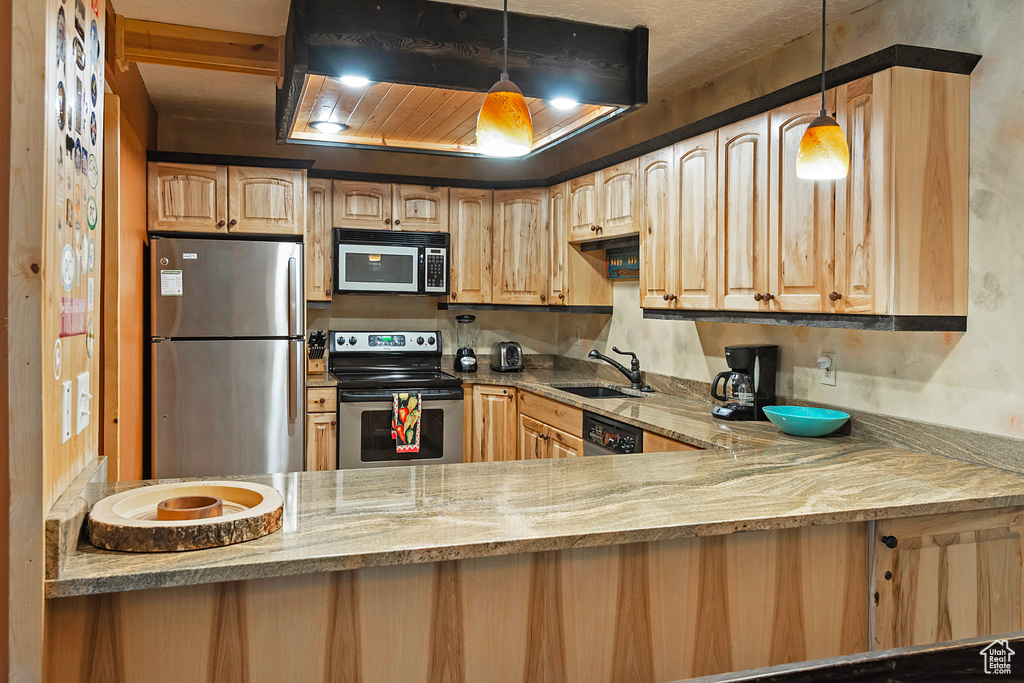 Kitchen featuring appliances with stainless steel finishes, sink, pendant lighting, and light stone counters