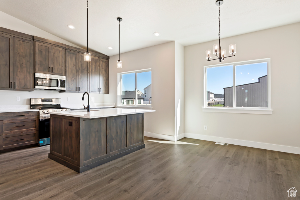 Kitchen featuring a center island with sink, dark hardwood / wood-style flooring, appliances with stainless steel finishes, and pendant lighting