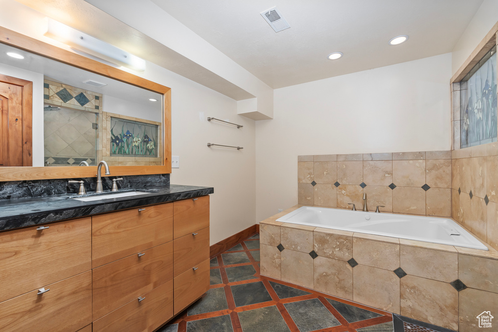 Bathroom with tile flooring, tiled tub, and vanity