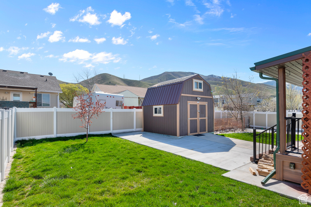 View of yard with a patio area, a mountain view, and a storage shed