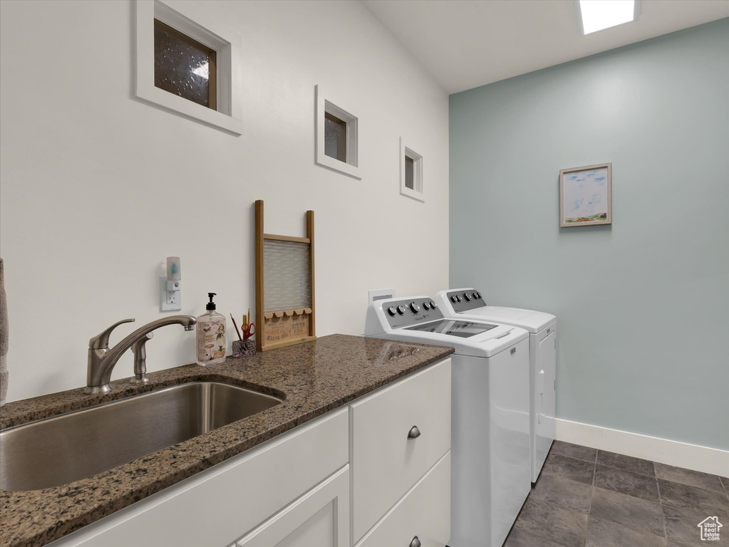 Laundry room with separate washer and dryer, hookup for a washing machine, sink, dark tile flooring, and cabinets