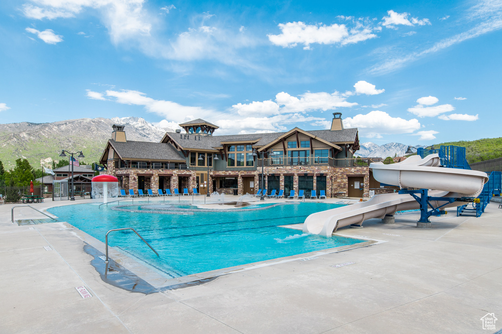 View of swimming pool with a patio, a mountain view, pool water feature, and a water slide