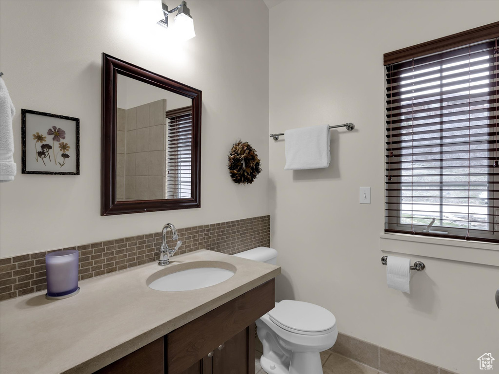 Bathroom featuring backsplash, toilet, tile floors, and vanity